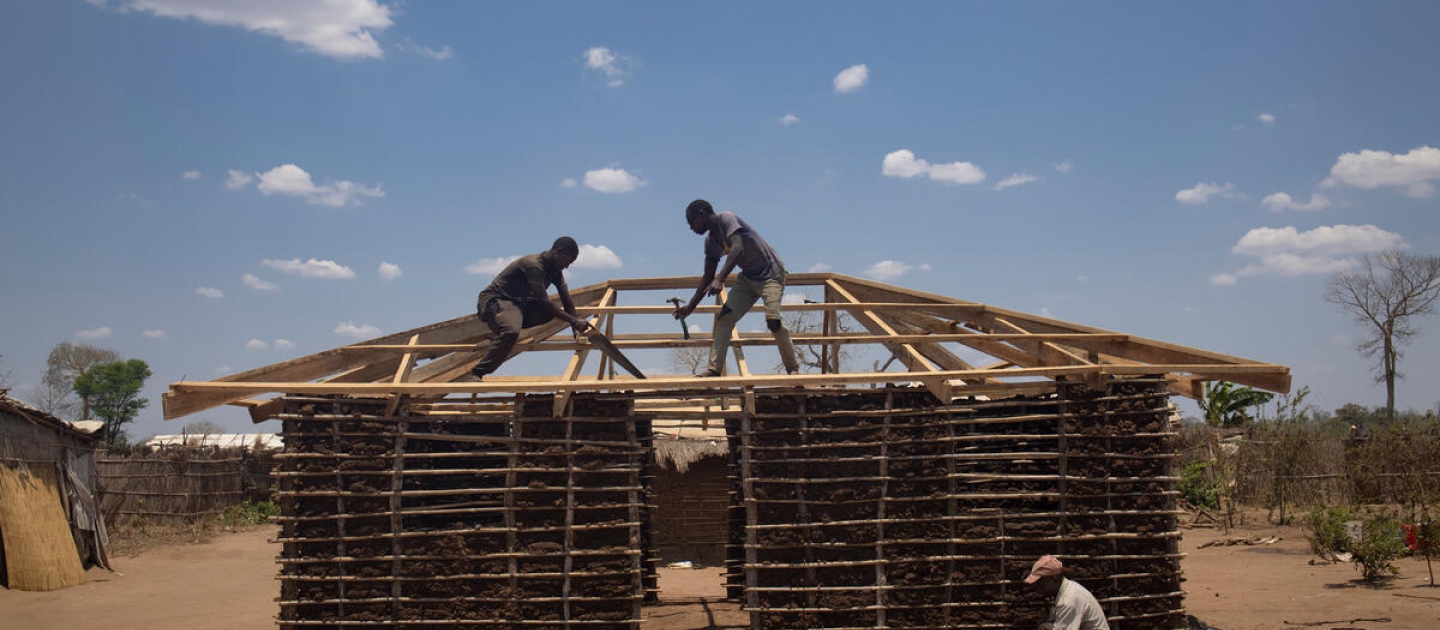Mozambique. Workers build new house for displaced family