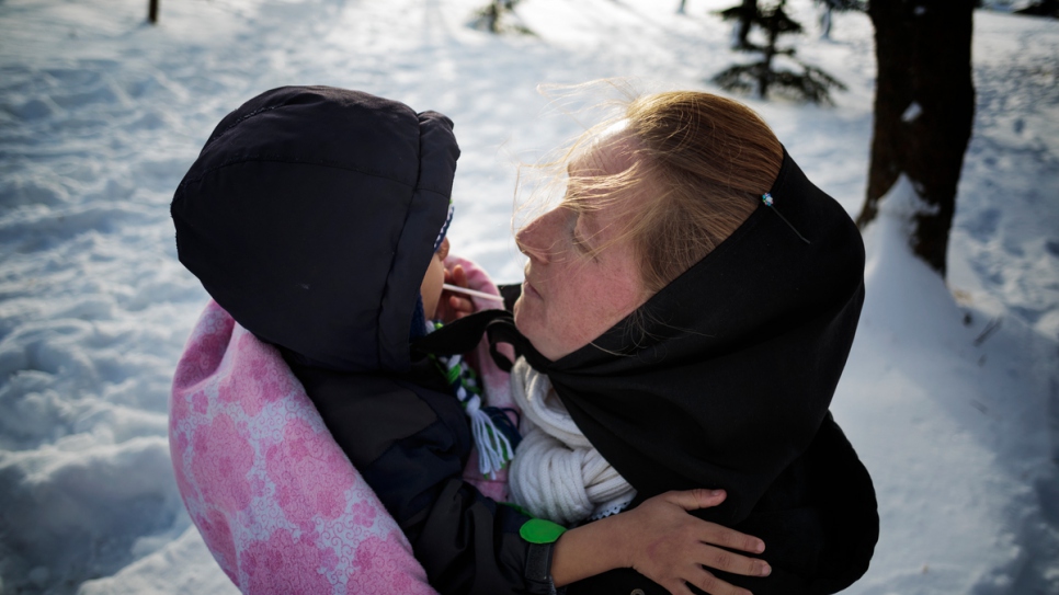 Elaine Hofer wraps Ali Al Hamoud in a blanket after the young Syrian spent the early afternoon in the snow.