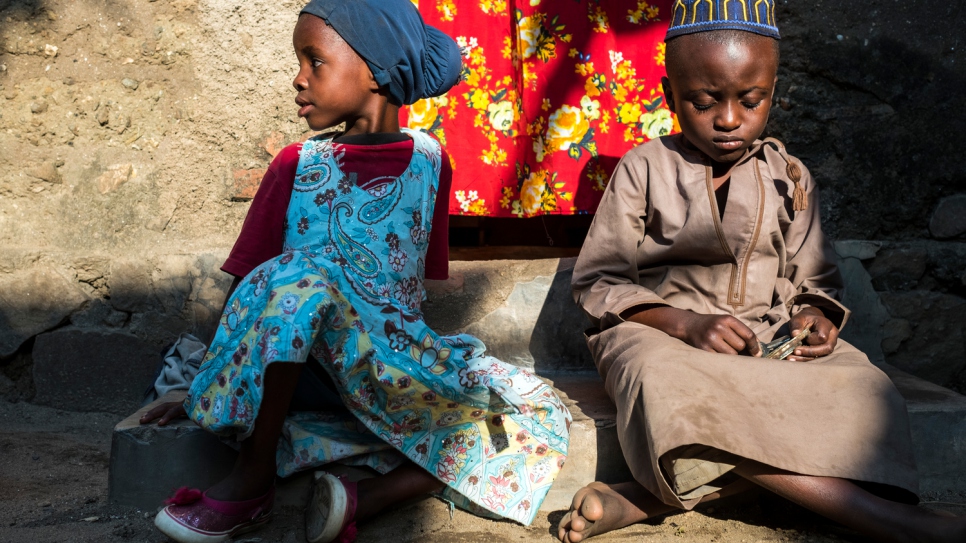 Two of Rehema's grandchildren sit on the doorstep of their home in Uvira. They fled Burundi with their grandmother after her sons were killed. Now, five of them live in two small rented rooms, struggling to make ends meet.
