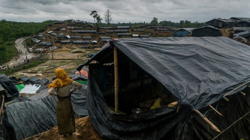 Devant l'entrée de son abri, une réfugiée rohingya regarde une installation informelle à Thangkali, au Bangladesh.