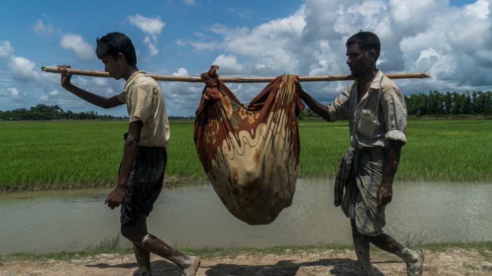 Mabia Khatun (unseen in blanket), a 75-year-old Rohingya refugee, is carried by two of her sons after crossing from Myanmar, near Whaikhyang, Bangladesh.