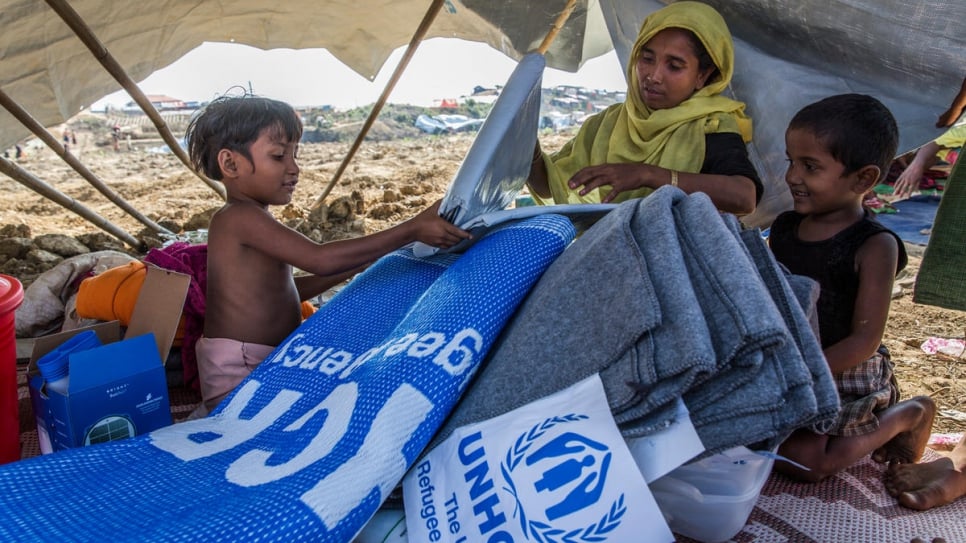 Laila Begum, 30, and her children open an aid pack – including a solar lantern, phone charger, blankets, tarpaulin and kitchen set – at Kutupalong refugee camp on November 20.
