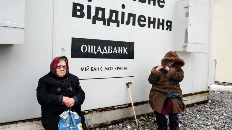 Nelia (left) spent hours waiting beside this mobile bank at Novotroitske checkpoint.