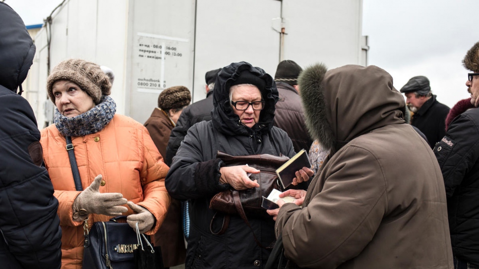 Elderly people cross at Novotroitske checkpoint to withdraw their pensions.
