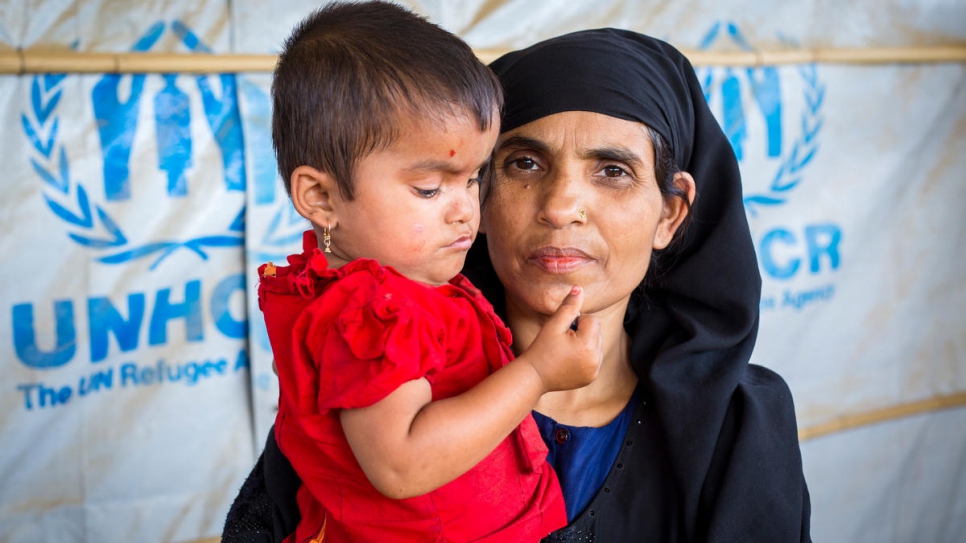 Khatemunnesa, 40, holds her daughter at a UN Refugee Agency Information Point in Kutupalong refugee settlement, Bangladesh.

