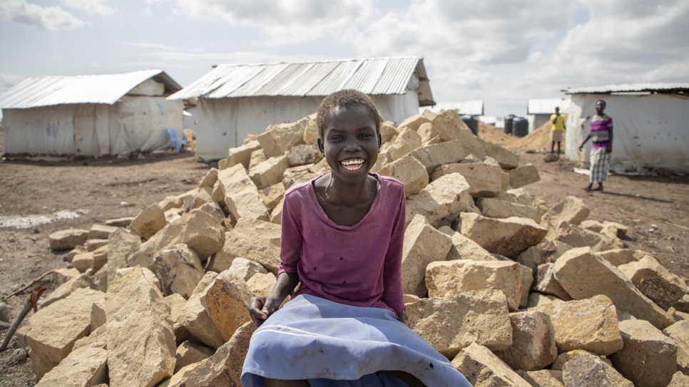 Betty Dikun, une réfugiée sud-soudanaise originaire de Fajalik, assise sur le tas de pierres qui serviront à la construction de la future maison de sa famille dans le cadre d'un projet d'aide en espèces pour la construction d'abris au camp de Kalobeyei. 