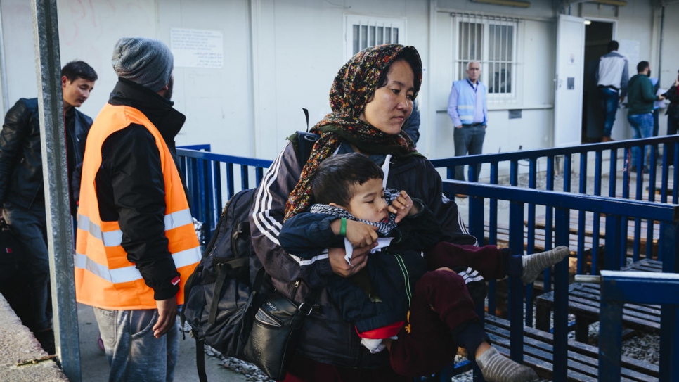 An asylum-seeking woman from Afghanistan carries her young son into the registration area of the Moria Reception and Identification centre on the Greek island of Lesvos.