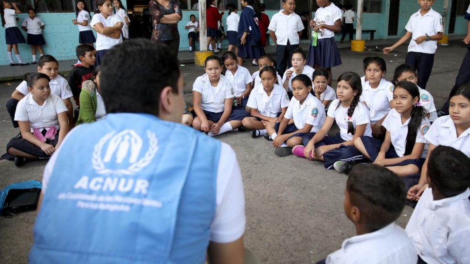 UNHCR senior child protection assistant Juan Camilo Jiménez talks in November, 2019, to children at the Simón Bolívar School in Tegucigalpa, Honduras, about forced displacement.