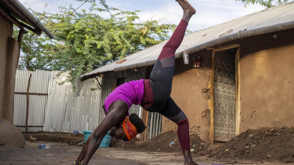 Rita Brown, a Ugandan refugee and yoga instructor, strikes a yoga pose outside her compound in Kakuma camp, Kenya.