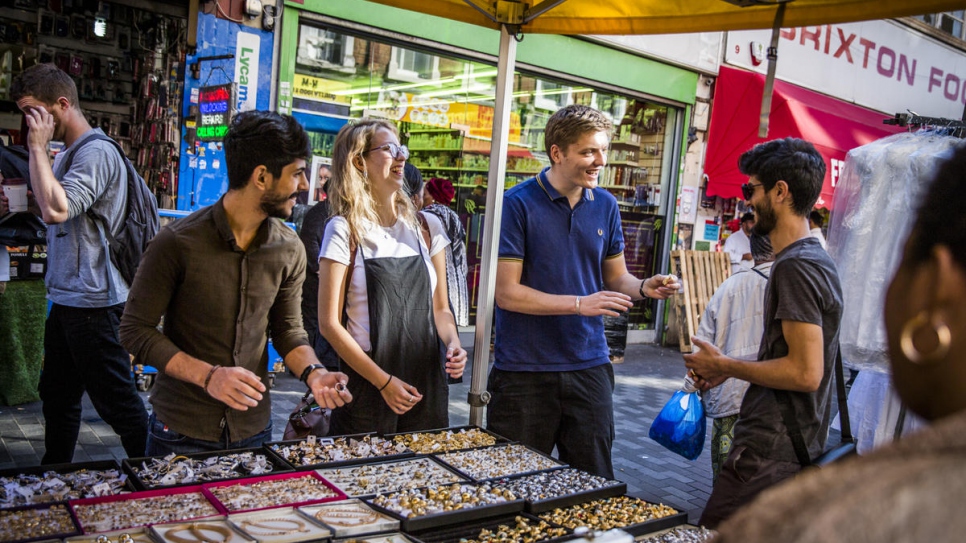 Syrian refugee brothers, Mohammed (wearing sunglasses) and Lutfi Al-Shaabin, check out a jewellery stall in Brixton Market, London, with Bea Forrester and Todd Baker of Peckham Sponsors Refugees. The local group, founded by Bea, are sponsoring the Al-Shaabin's resettlement in the UK.