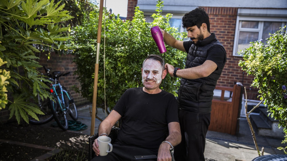 Syrian refugee Lutfi Al-Shaabin cuts Tim Finch's hair at the Al-Shaabin home in south London. Lutfi was a barber in Jordan where his family lived as refugees. Tim is a member of Peckham Sponsors Refugees, a local residents group sponsoring the family's resettlement in the UK.