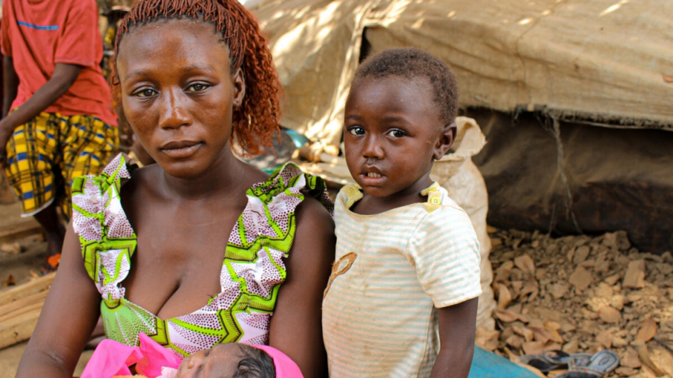 Benitia, une réfugiée centrafricaine de 23 ans, tient son bébé dans les bras alors que sa fille Safira se tient près d'elle dans le village de Ndu, en République démocratique du Congo.  