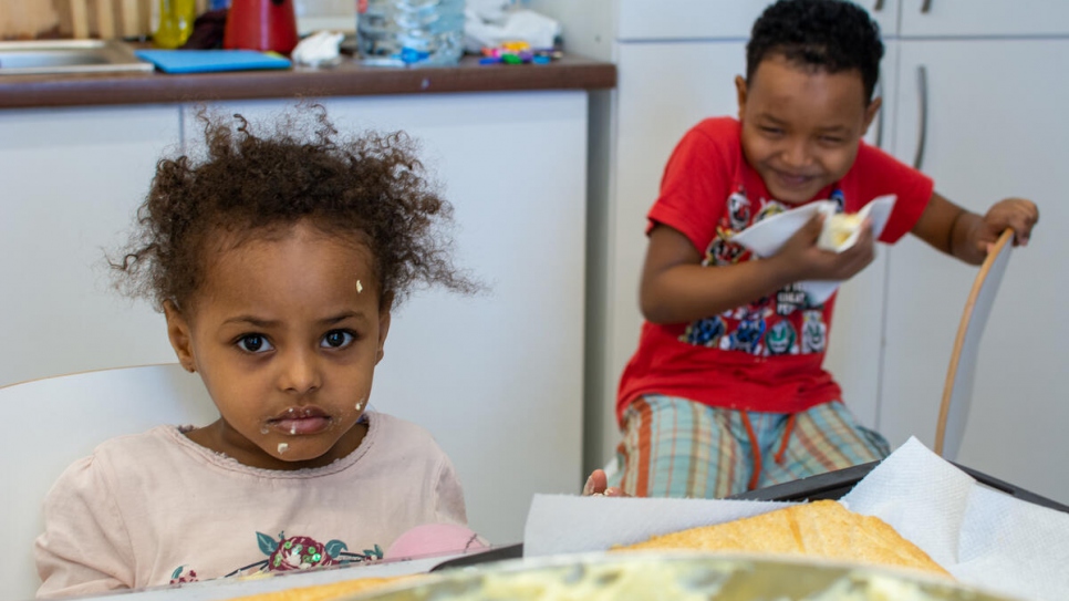 Feruz (5) and Karim (7) eating the tompouce their mother made during a cooking workshop organized by AIDRom, UNHCR's partner in the Emergency Transit Centre in Timisoara, Romania. February 2021 ©UNHCR/Stefan Lorint