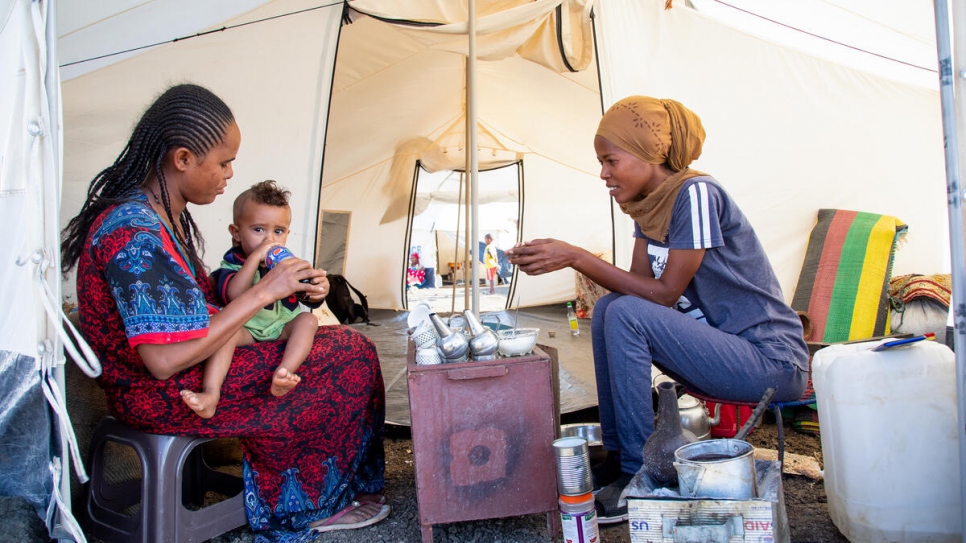 Mihret, 25 ans, discute avec sa tante alors qu'elle prépare le café éthiopien traditionnel dans son abri du camp de Tunaydbah, au Soudan.