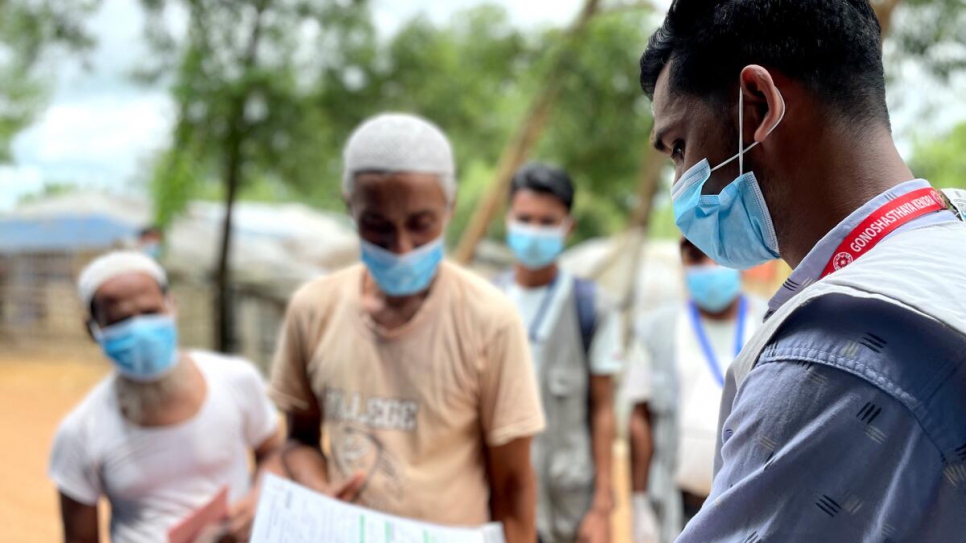 Humayun Kabir, a Bangladeshi community health worker, helps Rohingya refugees waiting to receive their first COVID-19 vaccine.