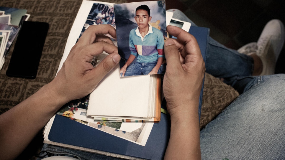 Santiago penché sur les photos de son jeune frère assassiné à l'âge de 16 ans par des membres de gangs. La tragédie a contraint le reste de la famille à fuir son foyer. 