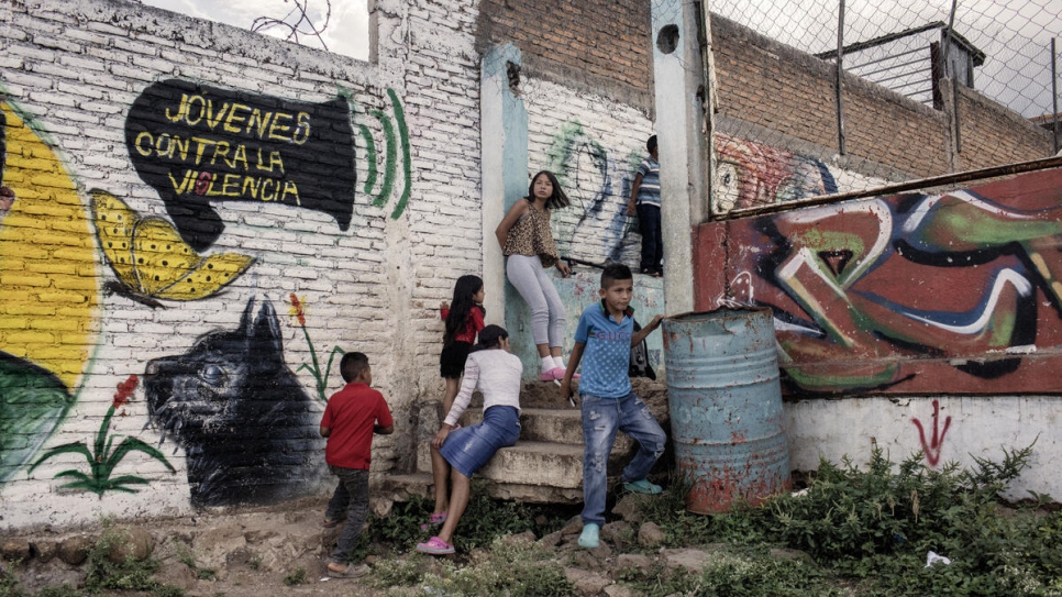 Children stand next to graffiti created as part of Jóvenes Contra la Violencia's activities in Nueva Capital, Honduras.
