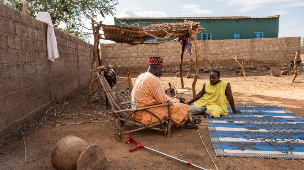 Madiega sits with his neighbor, Soumaila Ourdraogo, who agreed to host two internally displaced families on his land.