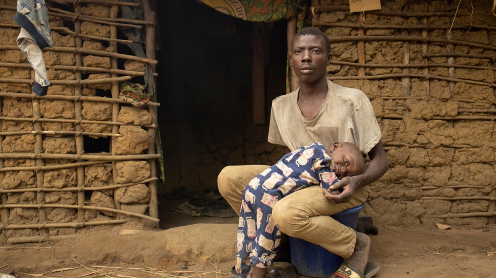 Mawaki Ngandibi, 24, sits with his 18-month-old son Doudé in front of his home in Ngoulayo, Republic of the Congo.