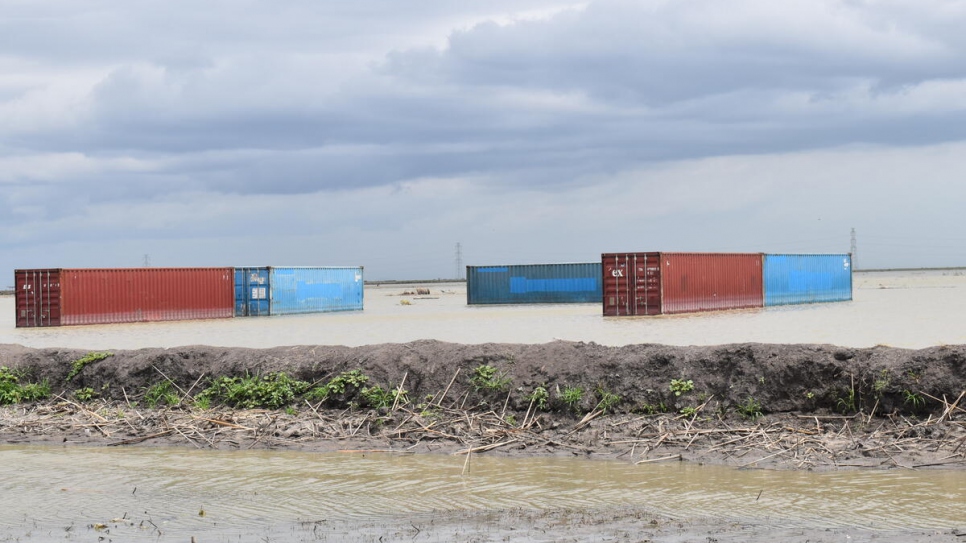 Les conteneurs du HCR qui ont résisté aux inondations dans le camp d'Alganaa sont visibles de l'autre côté du camp inondé.