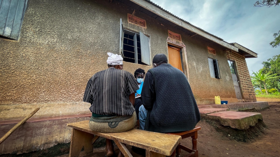 Jean* and his wife Maria* are interviewed by a UNHCR staff member at their home in Mukono district, Uganda.