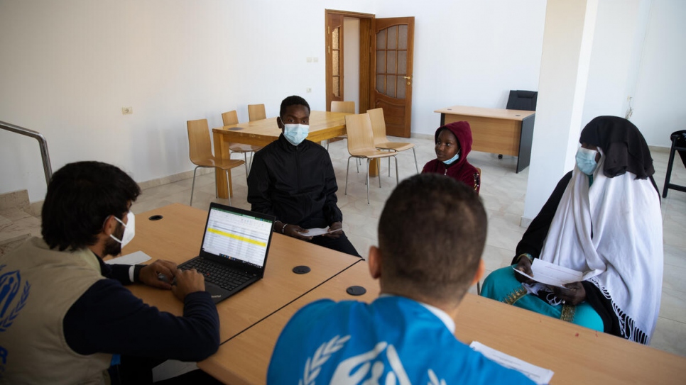Des employés du HCR à Tripoli offrent des conseils à Zahra, une demandeuse d'asile soudanaise, et à sa famille avant leur départ pour l'Italie.