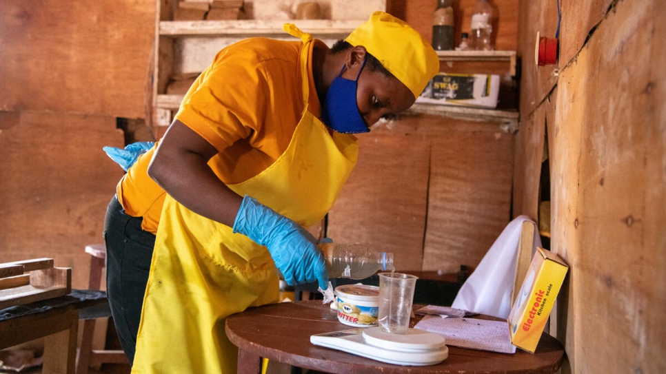 La Burundaise Aneilla Nizeyimana pèse soigneusement les ingrédients nécessaires à la fabrication de savon dans sa boutique du camp de réfugiés de Mahama, au Rwanda. 