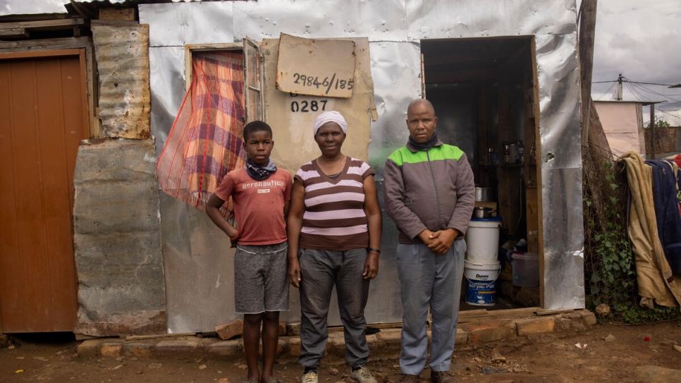 Bonisiwe, 52 ans, et ses fils Bhutinyana, 13 ans, et Mthokozisi, 35 ans, devant le logement d'une pièce qu'ils partagent dans le bidonville de Mamelodi près de Pretoria, en Afrique du Sud.  
