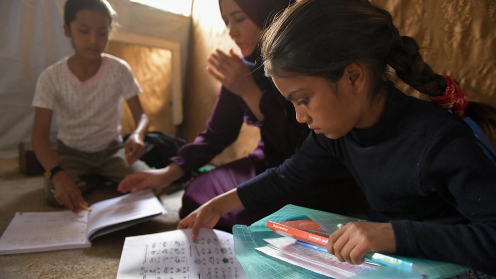 Majida's daughters Sara (right) and Aya (left) do their homework in the family's shelter.
