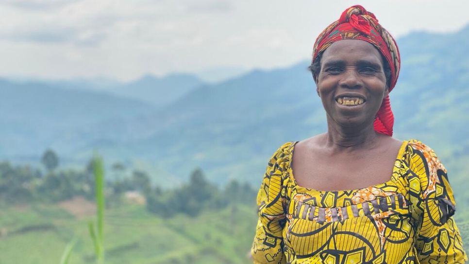 Asiteri Nyirasinamanye, 52 ans, pose à l'extérieur, avec les terres agricoles de Masisi en arrière-plan. 