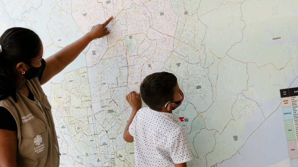 Lucetti and her 8-year-old Keiver examine a giant map of Manaus that hangs in her workplace, the UNHCR partner Caritas.
