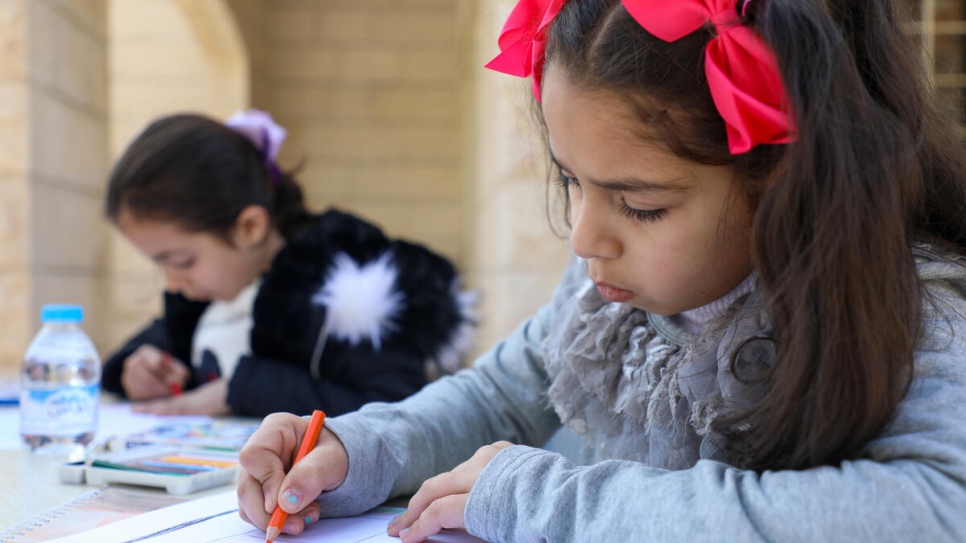 Mais, 7, (L) and Marah, 9, (R) draw images of Syria at a community centre in Madaba, Jordan.