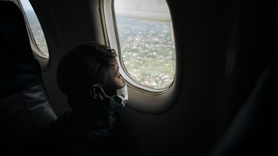 A young refugee looks out of the plane window during the repatriation flight.