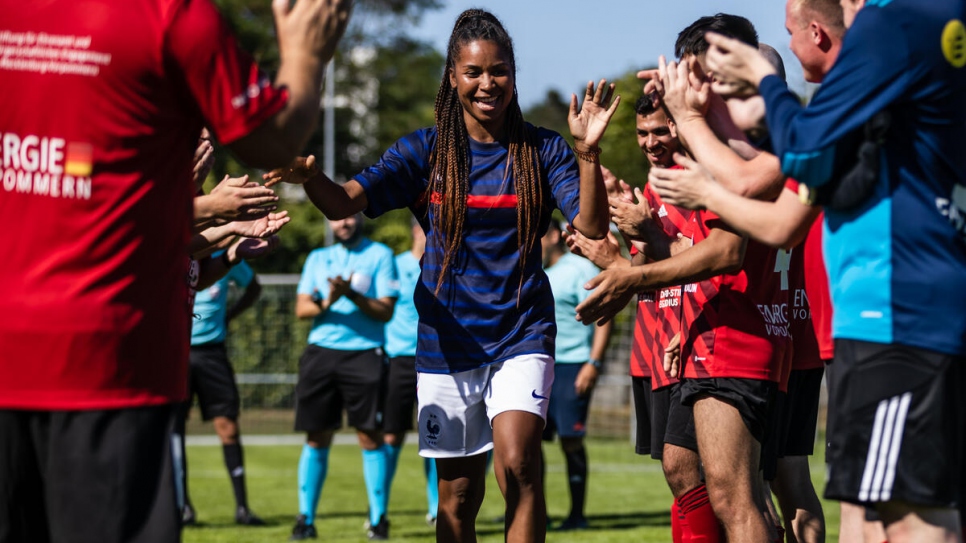 French team ambassador and former national team footballer Laura Georges (C) is greeted by the players.