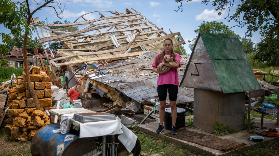 Svitlana with the family's dog, Bonita, stands next to what remains of the family home.