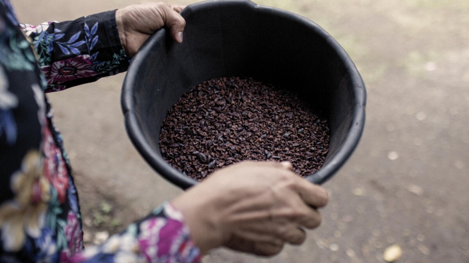 Carmen*, une demandeuse d'asile âgée de 38 ans et originaire du Nicaragua, tient des fèves de cacao séchées dont elle a enlevé la peau - une étape du processus de transformation du chocolat. 