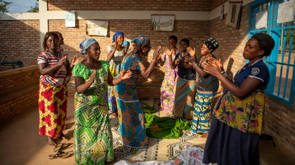 Ngena (centre, blue dress) and her companions sing together during a break from their work.