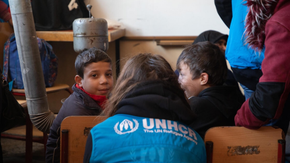 A UNHCR staff member talks to children staying at a collective shelter in the Salahadin neighbourhood of Aleppo, Syria.