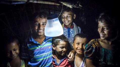Rohingya children sit beneath a solar lantern.