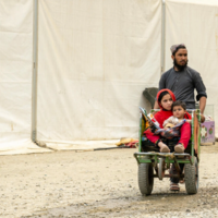 Hadigul is carrying his younger sisters, Sabria and Freshta, as they travel together after recently returning to Afghanistan. Despite the hardships they’ve faced, the close-knit family shows resilience and strength as they move forward.