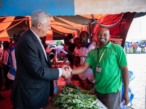 Two men shake hands at a vegetable stall.