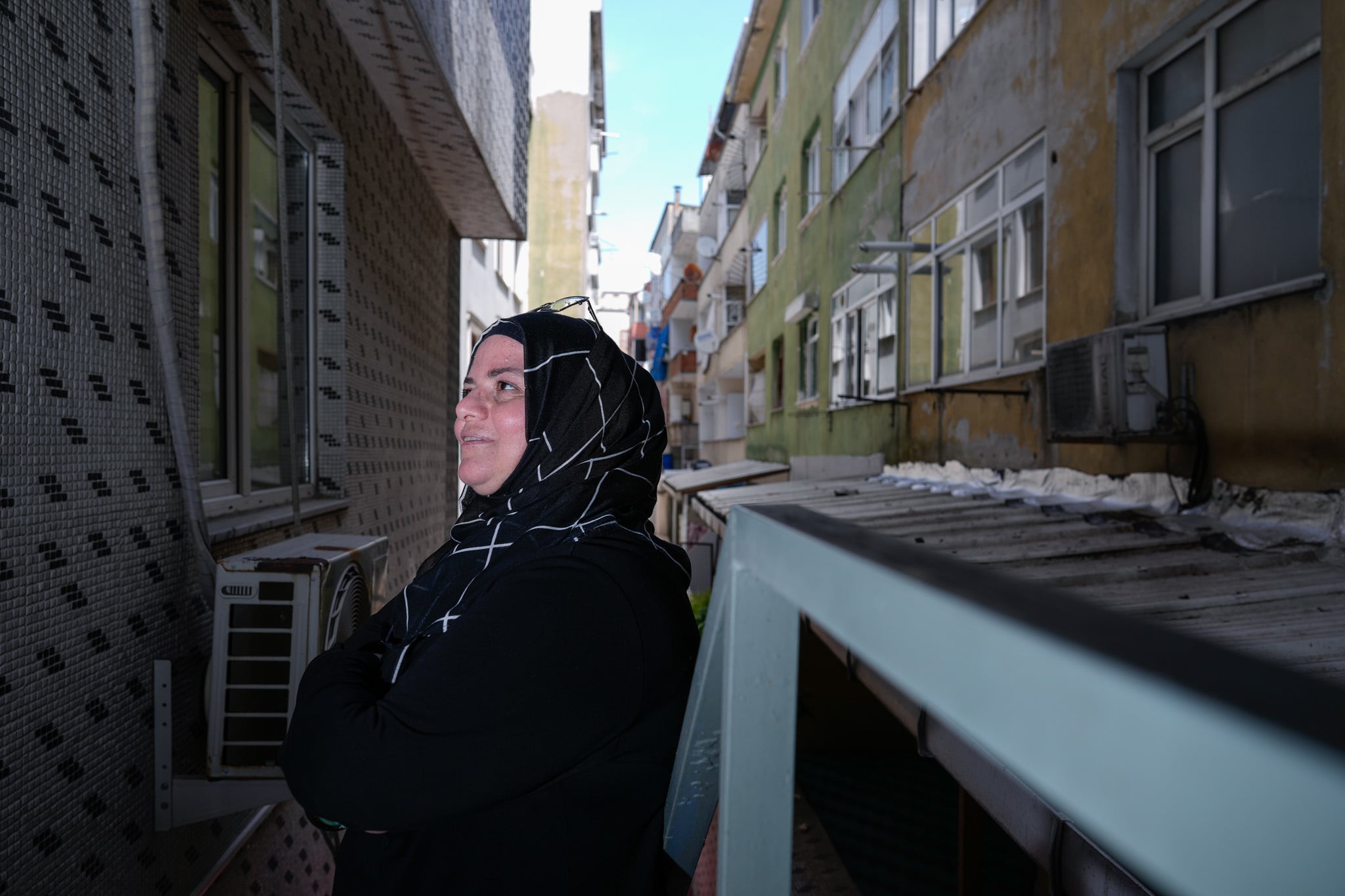 A person stands between apartment buildings in a narrow urban alleyway.