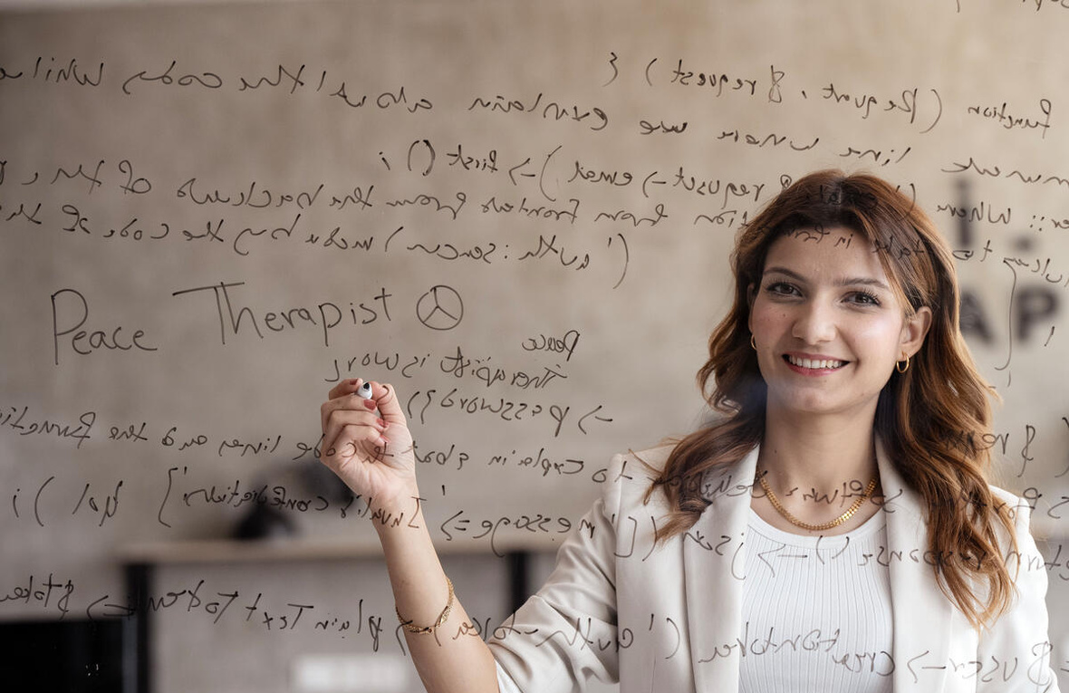 A young woman seen through transparent glass which is writing code on.
