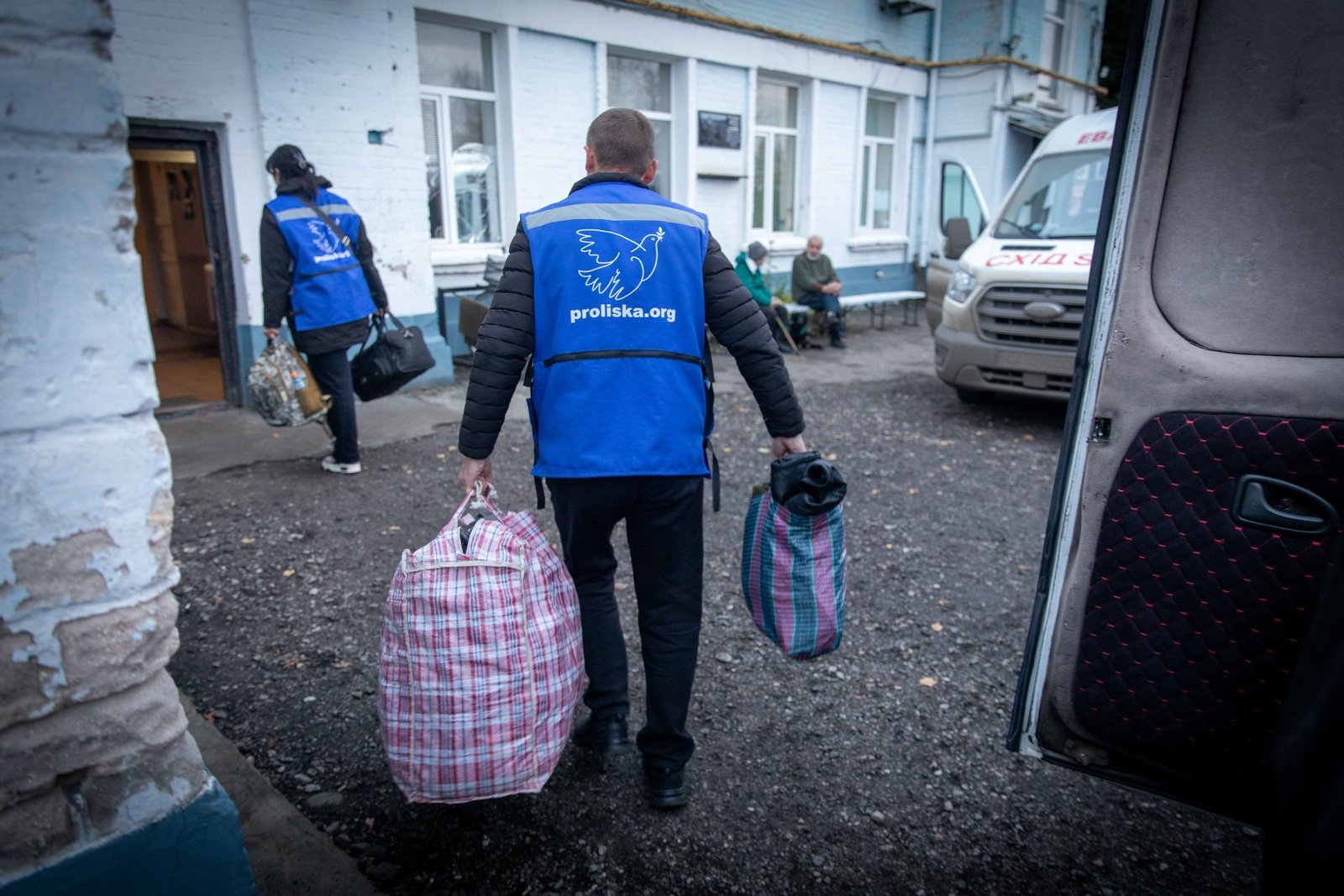 Proliska staff removing evacuee bags and belongings from an evacuation van in Oleksandrivka transit centre, Donetsk oblast