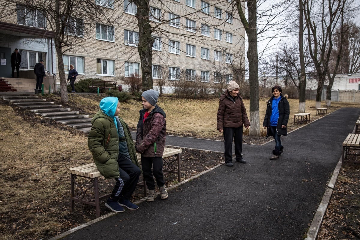 Some adults and some children gather outside a building
