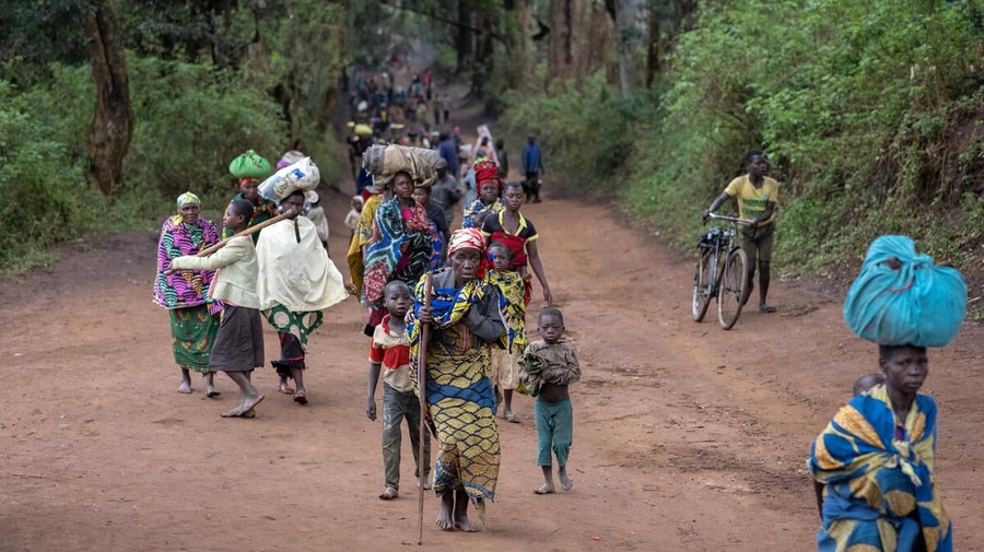 A group of displaced people walk along a road carrying their belongings, in the Democratic Republic of Congo.