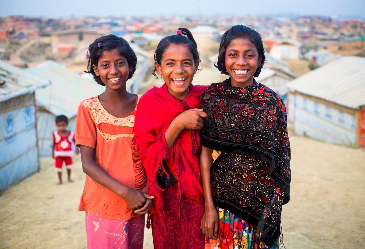 Three girls smile for the camera, in Kutupalong Refugee Camp.