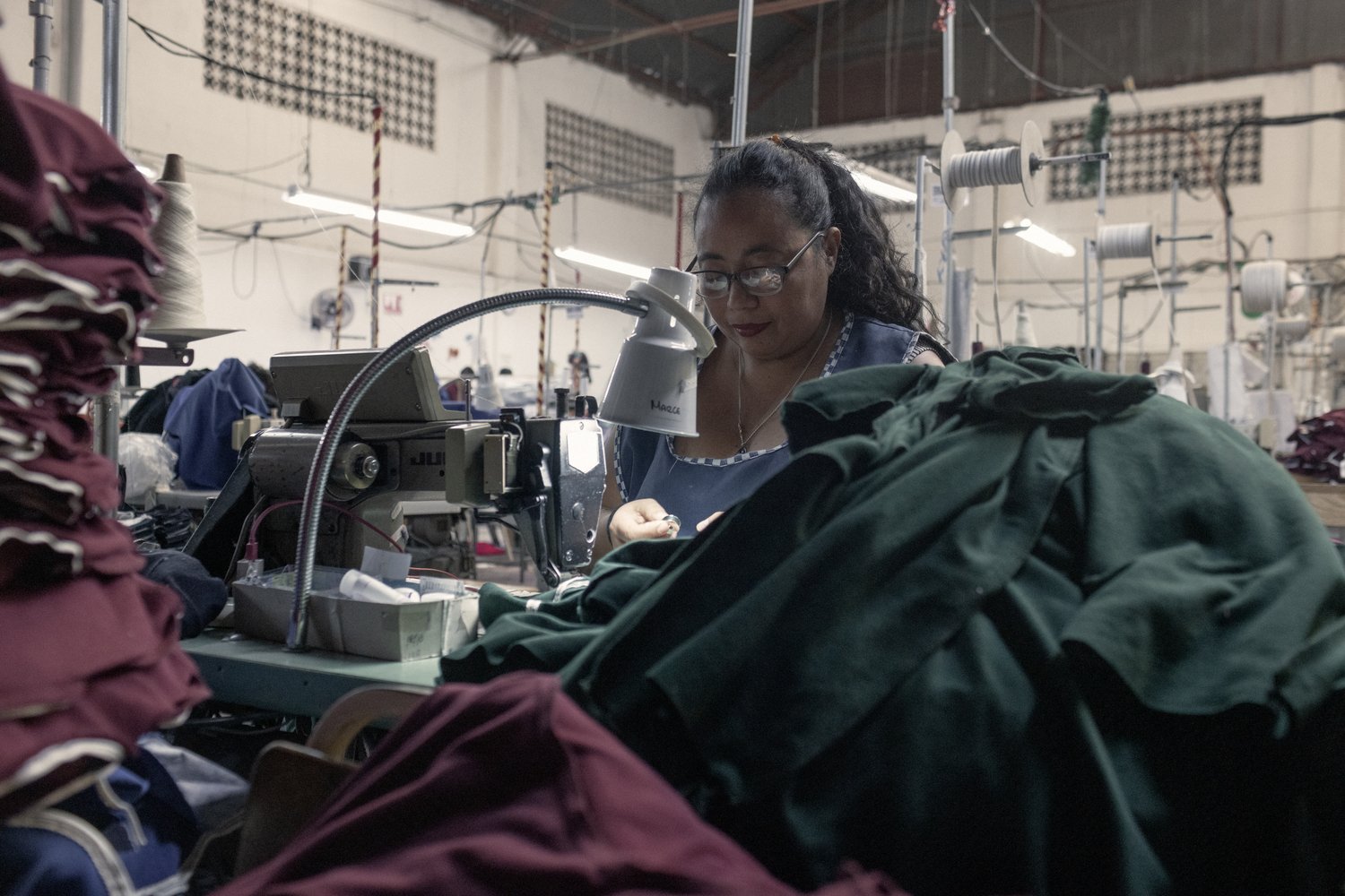 A woman in a factory works at a sewing machine.