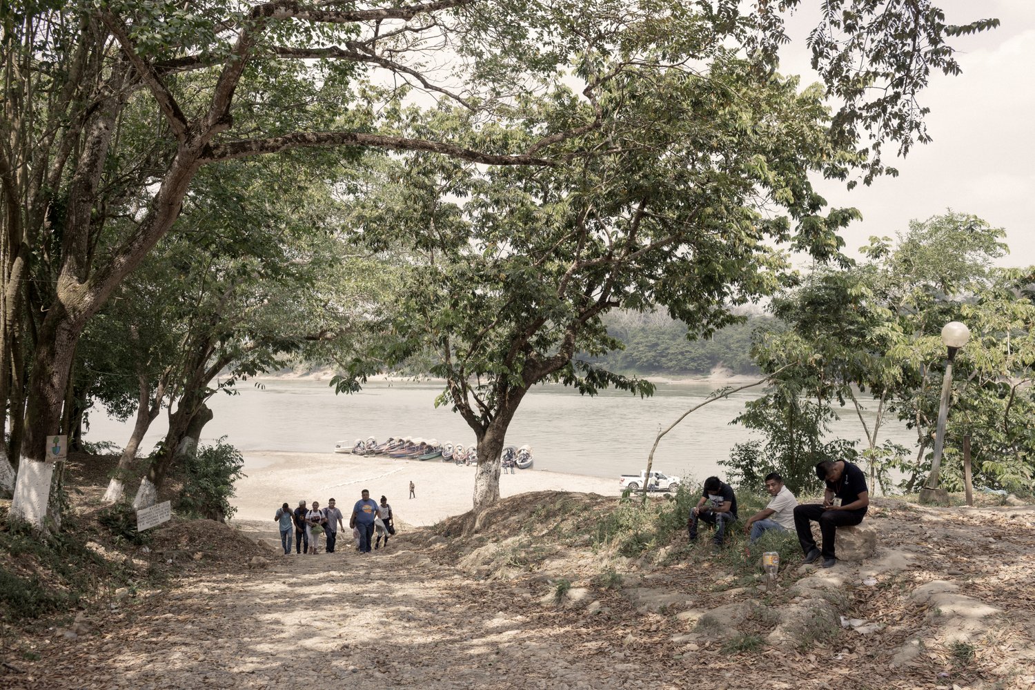 A group of people walk away from a river bank.