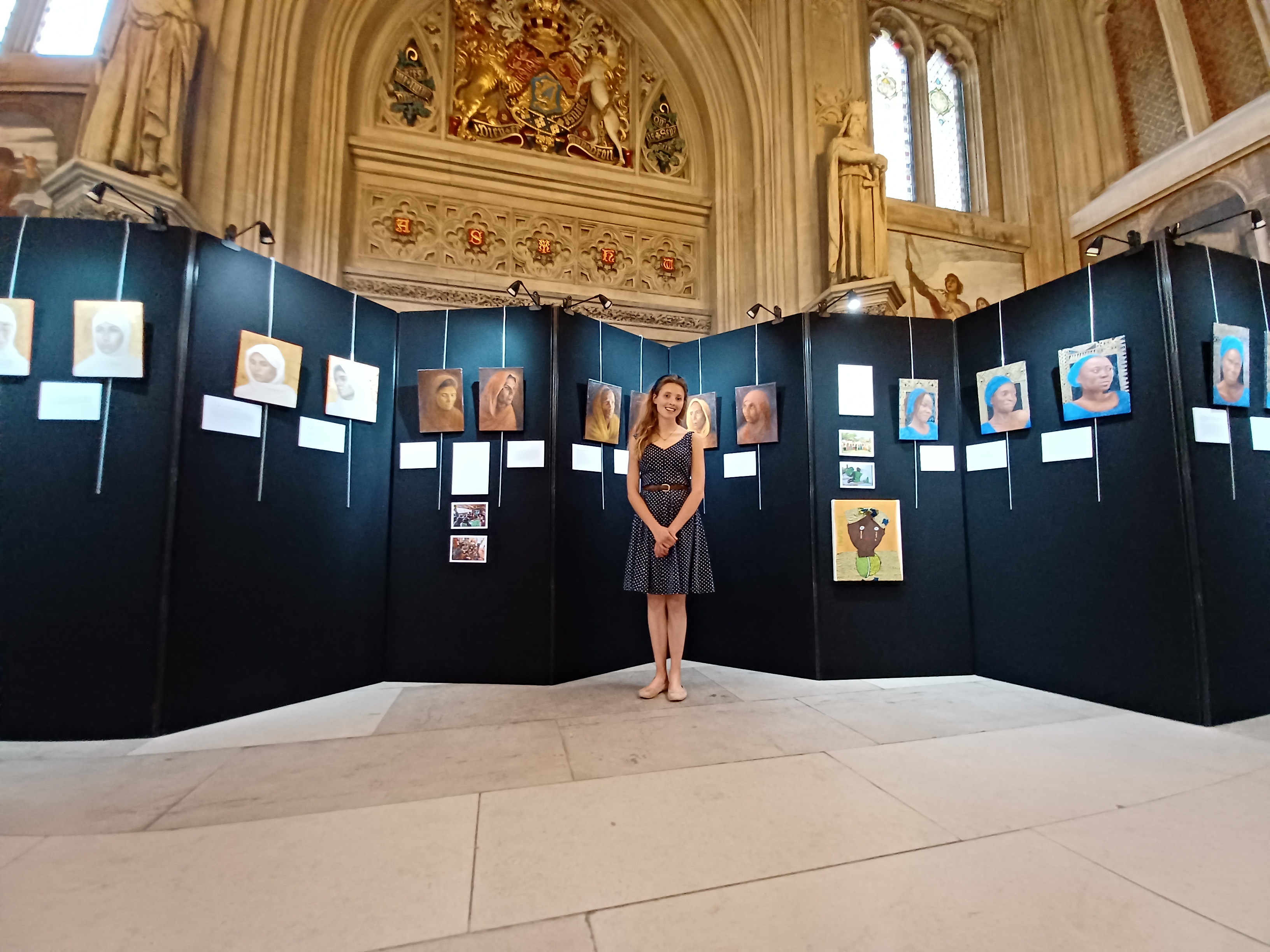 A woman stands infront of a series of paintings